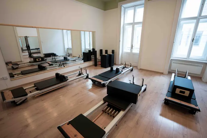 A BodyStudy stúdió világos terme tükörfallal, parkettával és több Pilates reformer géppel.